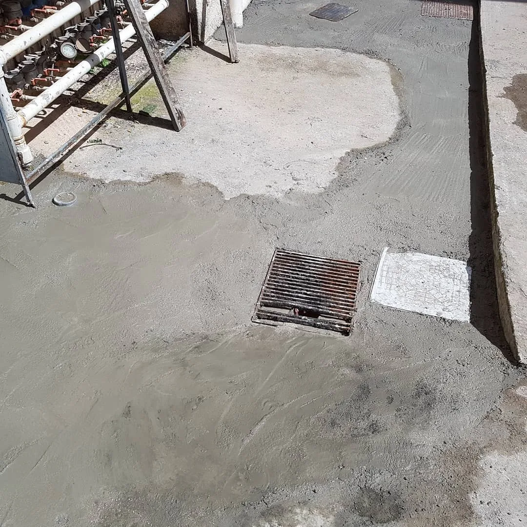 Αυλή πολυκατοικίας με νέο δάπεδο και φρεάτια μετά την αντικατάσταση της αποχέτευσης